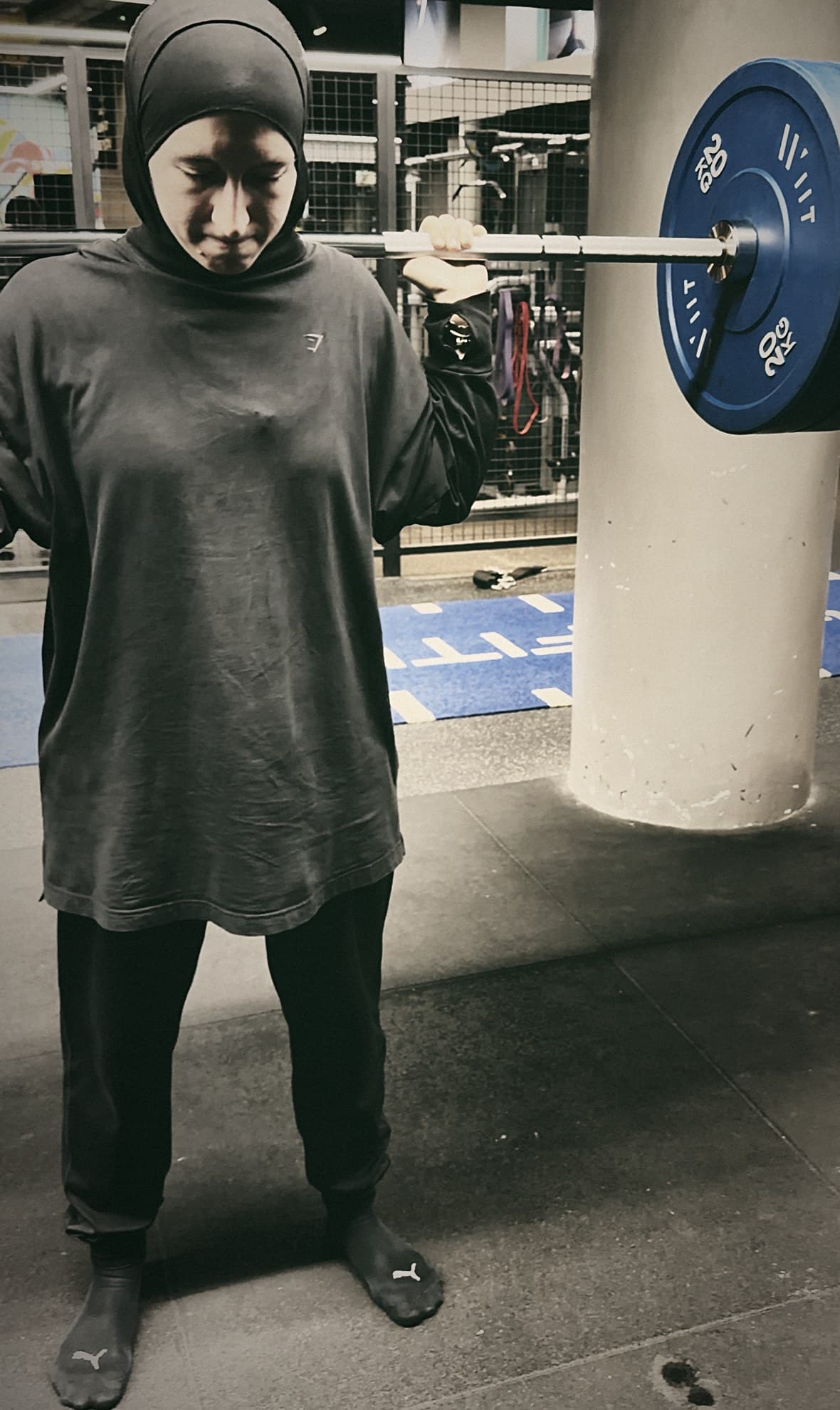 Katia in the gym, a loaded barbell across her shoulders.